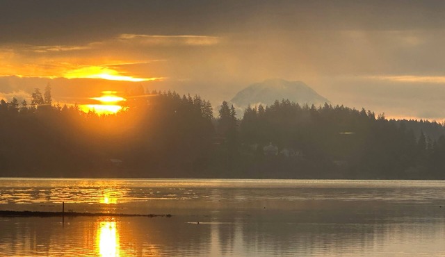 Family-friendly waterfront home with sunrise views of Mt. Rainier. Enjoy zero-bank access, kayaks, bocce, cozy fire pit, and hot tub. Plenty of space with 2 kings, queen + trundle, and queen Murphy bed. A perfect PNW escape minutes from Allyn.
